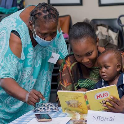 Community Project Corodinator, Thandiwe Khumalo, training the mother on sharing a book with her child.