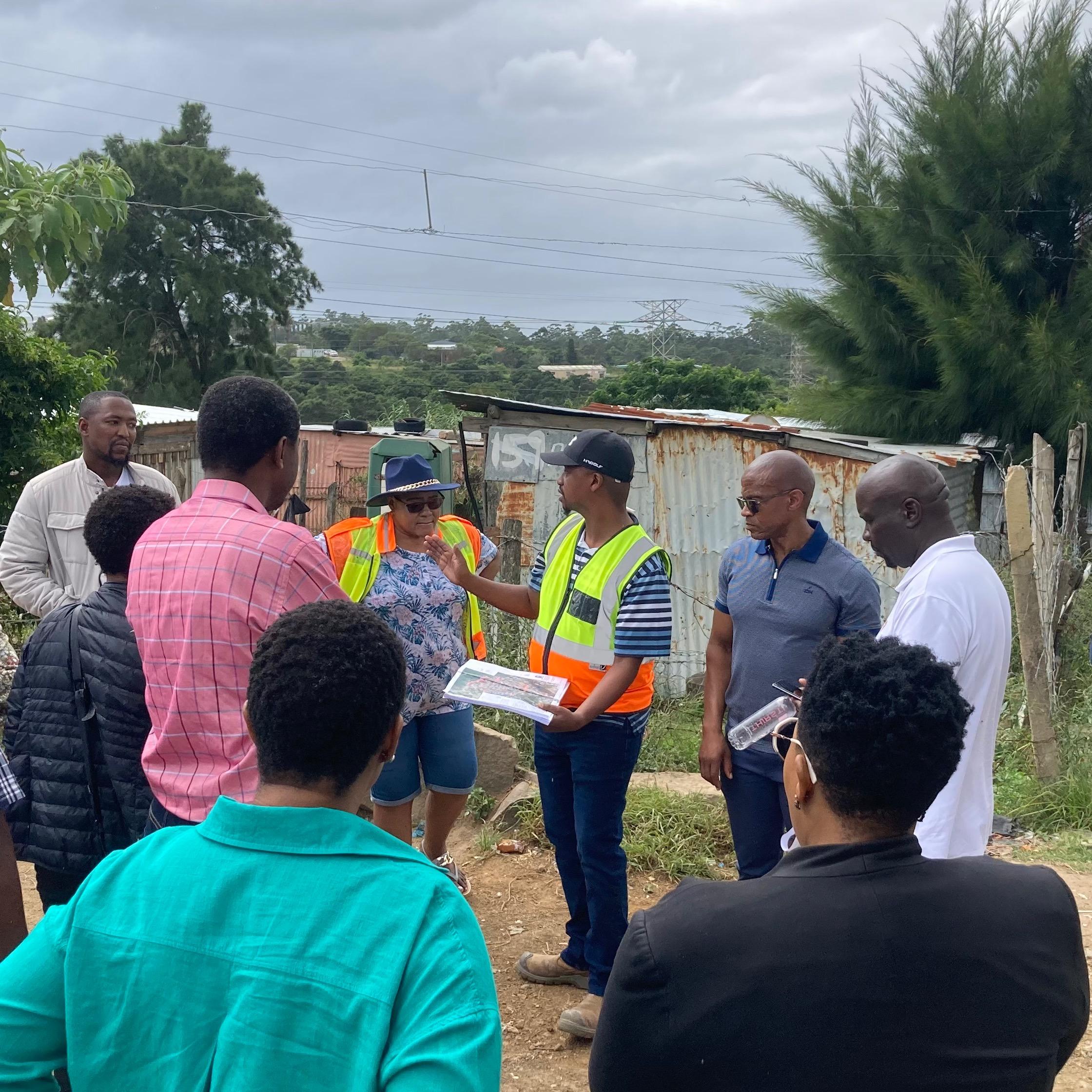 Afesis addressing the National Department of Human Settlement delegates visiting the reblocking pilot project in Phola Park Informal Settlement, Buffalo City Metro. Afesis who has the technical skills, has come alongside the residents of Phola Park who approached the organisation for help, as they have been waiting for housing and improved basic services for more that 20 years. They are voluntarily dismantling and relocating their shacks to make way for roads, toilets, and electricity.