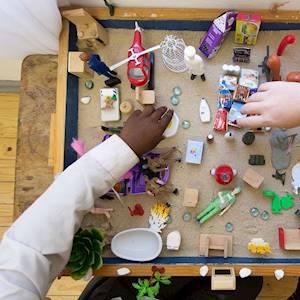 We do not always have the words to share our personal story, children (and adults) sometimes find it easier to express themselves through play. Here a therapist engages with one of our clients using sand tray therapy.